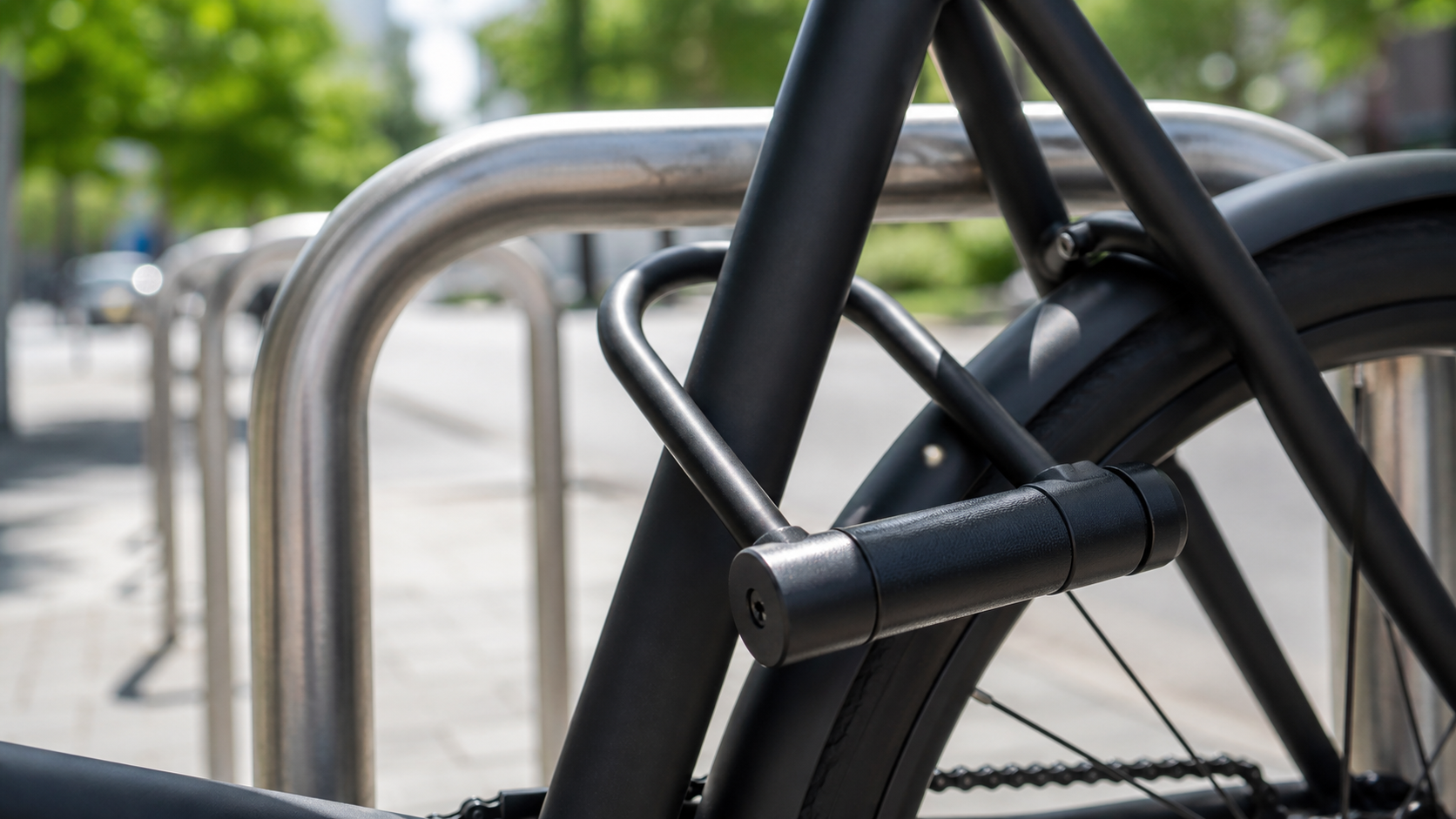 A close-up of a logo-free e-bike frame secured to a fixed rack with a U-lock.
