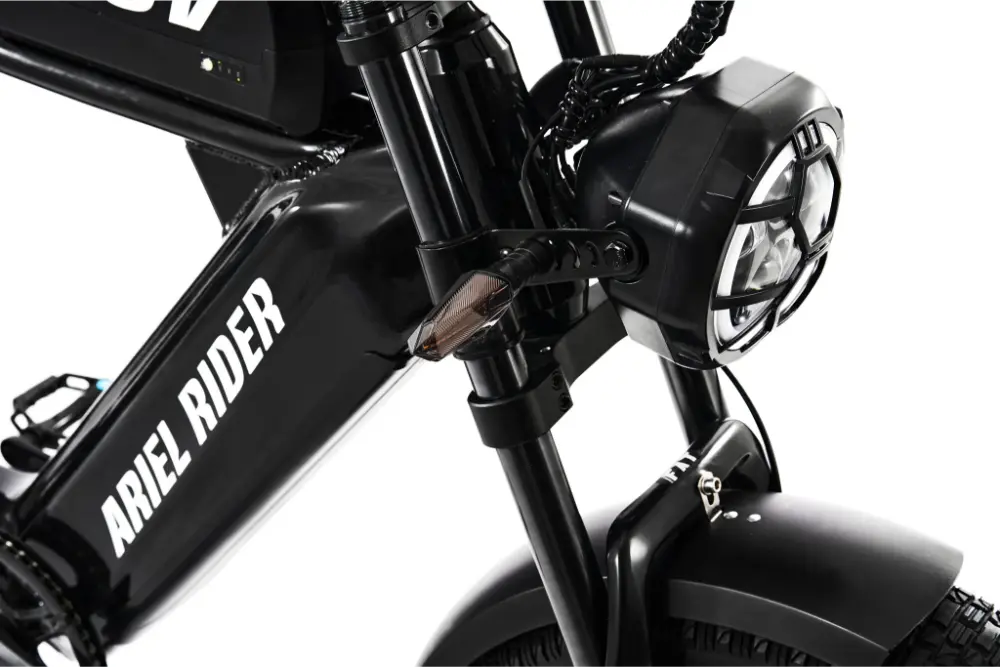 Close-up of a black Ariel Rider electric bike with headlight and front suspension. #Version_Cafe Racer