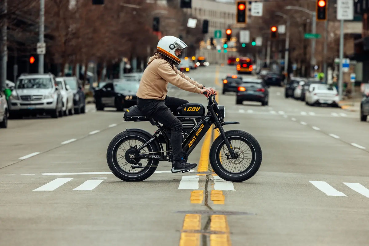 Rider commuting to work on Ariel Rider X-Class 60V fat tire e-bike in city traffic