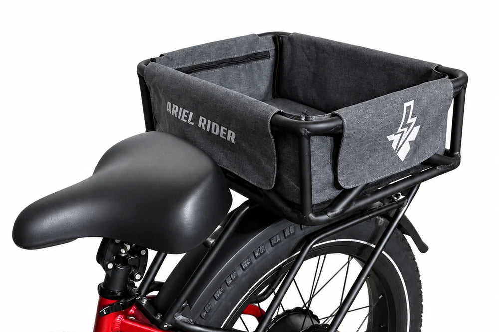 Side detail of the Ariel Rider rear cargo basket and gray liner, showing the white logo and black basket frame.