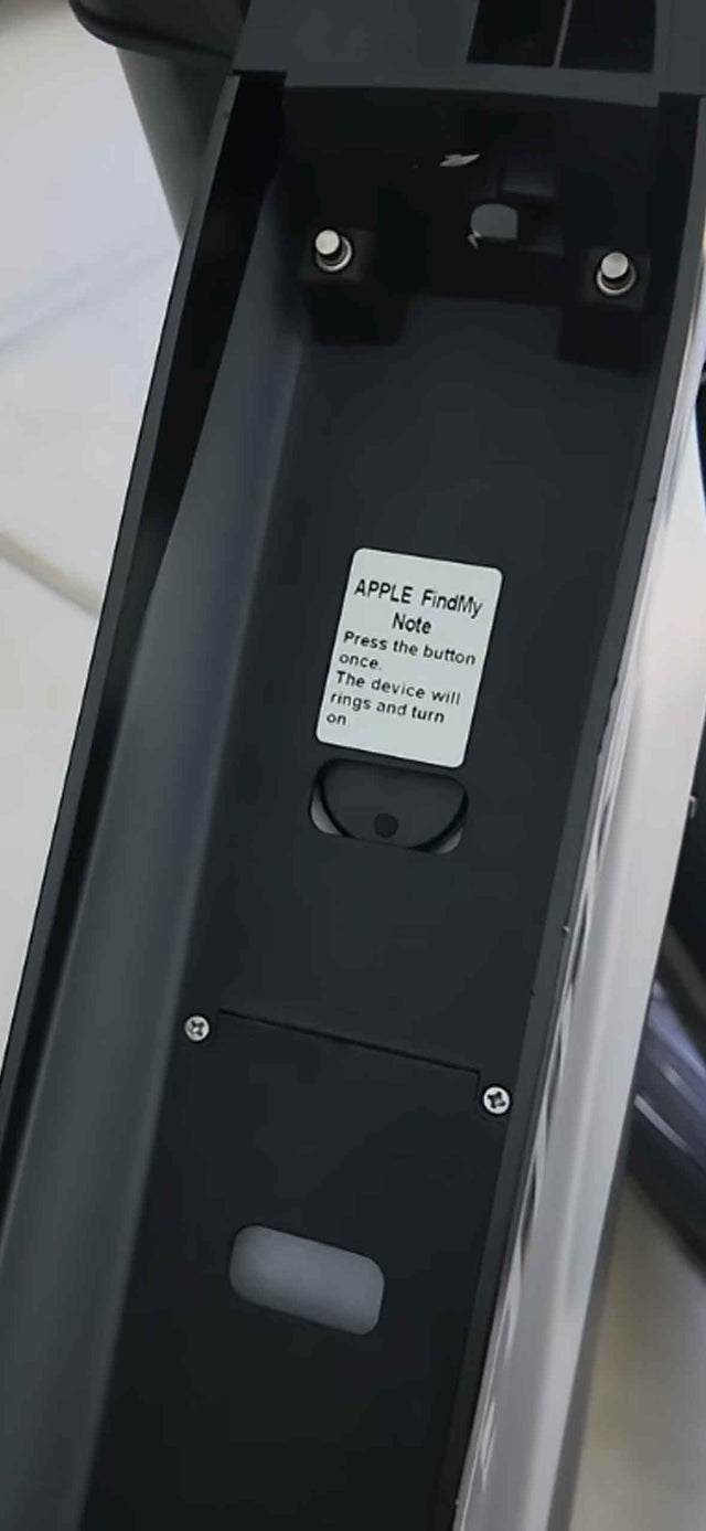 Close-up of the Apple Find My tracker button on an Ariel Rider e-bike frame with a press-to-turn-on label